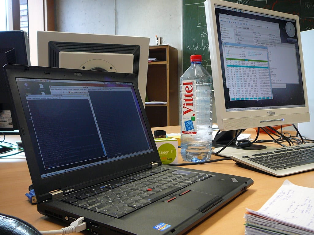 An external monitor and a laptop raised on a stand to align their tops