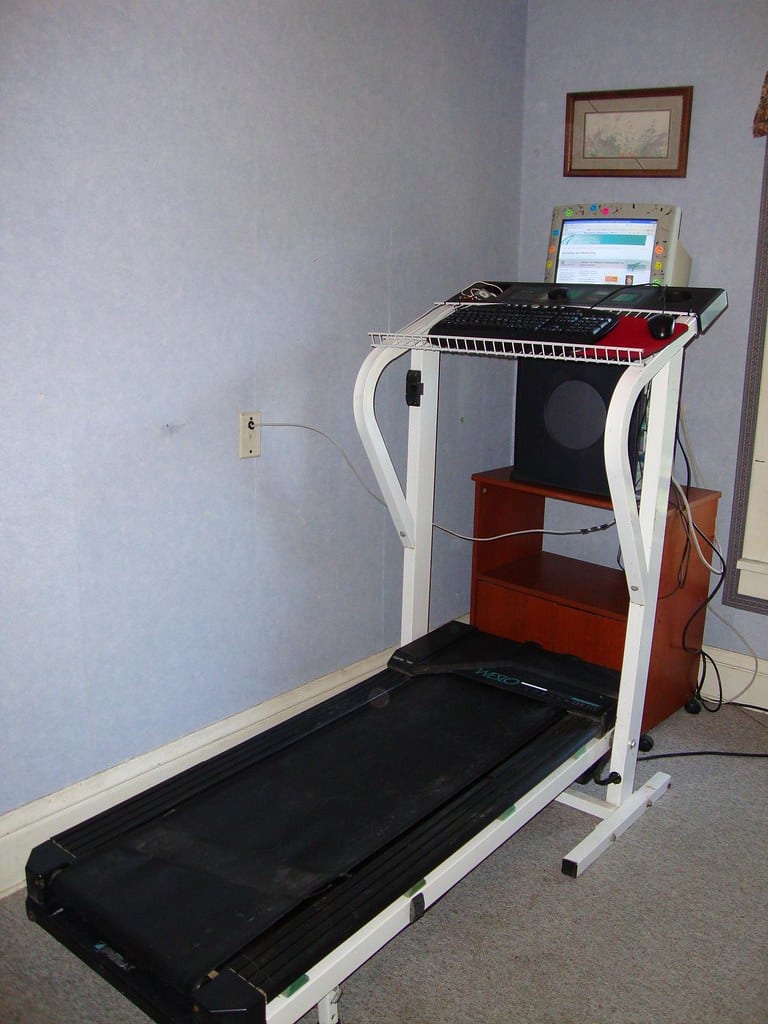 A monitor on an arm at a sit-stand desk raised to standing height